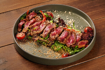 Sliced beef salad with parmesan and cherry tomatoes on wooden table