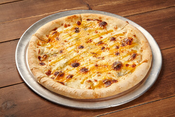 Four cheese pizza baking on wooden restaurant table