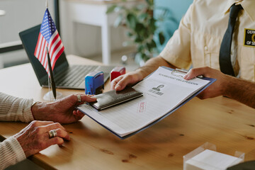 Elderly person discussing documents with visa officer at assistance meeting with files, passport,...