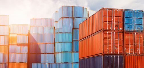 Fototapeta premium Economics and trade theme - foreground stacked containers with defocused port cranes behind