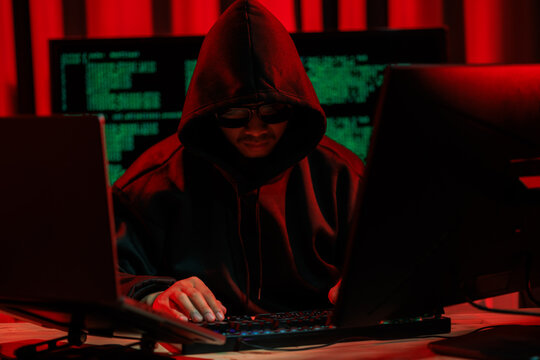 Lone hacker in a dark glowing room hacking data for cyber theft, symbolizing digital crime and online security threats.