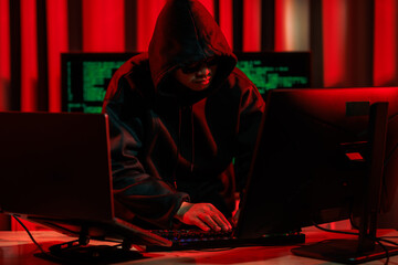A hacker operates in a dark room, stealing sensitive data through cybercrime — representing one...