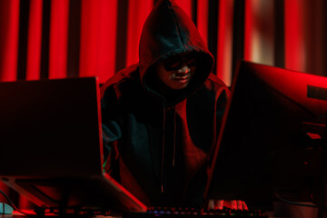 A hacker operates in a dark room, stealing sensitive data through cybercrime — representing one...