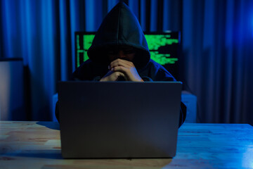 Male hacker in a dark room trying to steal global user data to sell on the dark web, representing...