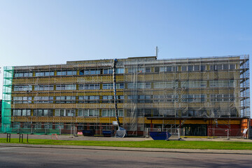 Renovation of office building covered in scaffolding and protective net during reconstruction work