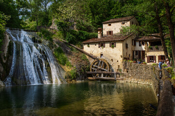 Old mill in the river in Refrontolo, Veneto, Italy, Molinetto della Croda, panorama with a beautiful waterfall in the woods and with people.