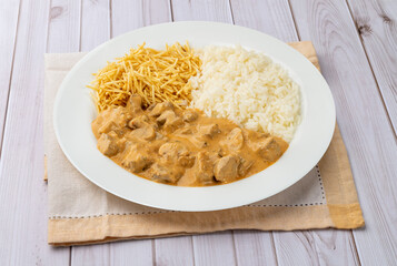 Meat strogonoff with rice and straw potato over wooden table