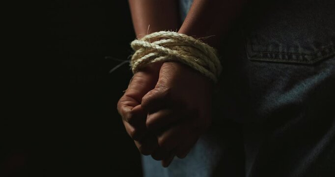 Hands, rope and prisoner for hostage, victim and kidnapping on black background. Capture, fear and restraint of person with censorship, bondage and domestic violence or human trafficking crime