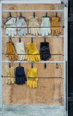 Rows of used heavy leather work gloves are stored in a trailer door, ready for use to keep hands safe.