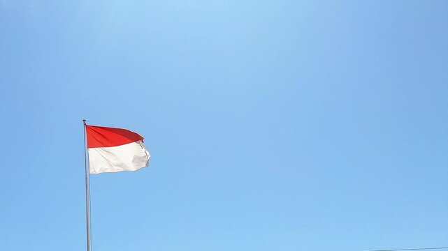 Low angle and Cinematic shot of the Indonesian National flag fluttering in the wind. Patriotism and Nationalism concept
