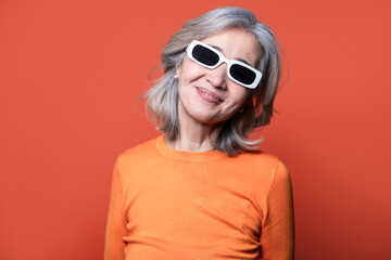 Stylish asian senior woman with orange theme and sunglasses