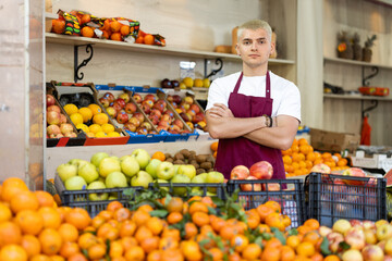Portrait of confident male seller in apron in interior of grocery supermarket