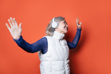 Joyful elderly asian woman enjoying music with headphones