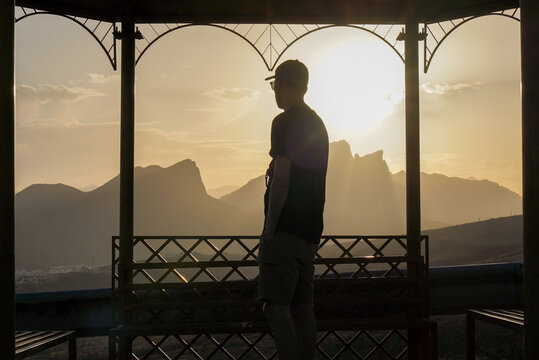Back view of unrecognizable man watching sunrise in Al Hamra, Oman