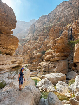 Woman exploring the rocky landscape of Wadi Ash Shab, oasis in Oman