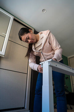 Assembling a white desk at home by young Asian woman