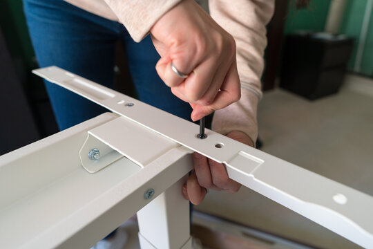 Woman assembling a desk at home using a screwdriver