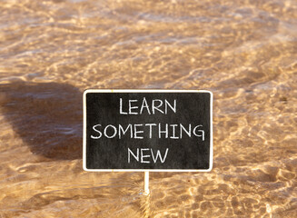 Naklejka premium Learn something new symbol. Concept words Learn something new on beautiful blackboard. Beautiful Red sea water background. Business motivational lifestyle learn something new concept. Copy space