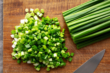 Organic Cut Green Onion Scallions on a Wooden Board, top view.