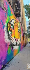 Fototapeta premium Colorful mural on the side of a building. the mural is of a tiger's face painted in bright colors, including orange, yellow, green, blue, and purple.