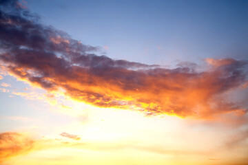 Sunset sky with layered clouds in various shades of blue, gray, and gold. A mesmerizing display of...