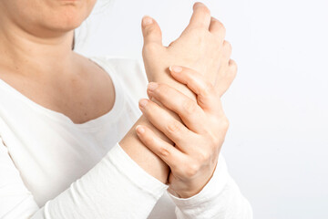 Arthritis symptoms, suffering from pain. The hands of the woman massage a painful wrist. Inflamed male joint, stiffness of movement. Close up view