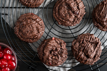 Triple Chocolate Cherry Cookies with Chocolate Chips and Candied Cherries: Chocolate chip cookies dark chocolate drizzle on wire cooling rack with a dish of glace cherries