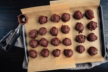 Scoops of Chocolate-Cherry Cookie Dough on Sheet Pan: Balls of cookie dough and cookie scoop on...