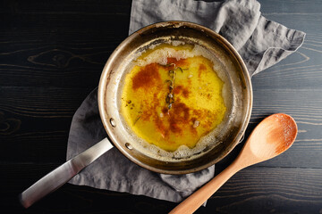 Browned Butter with Rosemary Sprig in Skillet: Brown butter infused with fresh rosemary in a stainless steel skillet