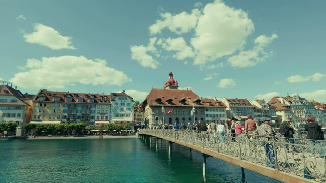 Der Rathaussteg in Luzern an einem sonnigen Tag &ndash; charmante Fu&szlig;g&auml;ngerbr&uuml;cke &uuml;ber die Reuss mit Blick auf Altstadt, Berge und klares Wasser, perfekt f&uuml;r Spazierg&auml;nge und Fotos.