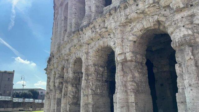 Ancient Roman Theater of Marcellus in Rome, Italy. Historic semi-circular stone structure resembling the Colosseum, lit by sunlight.

