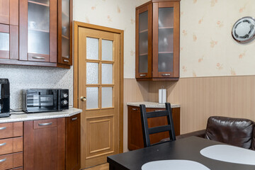 kitchen design in simple style. Built-in kitchen with wooden cabinets. Built-in appliances. Upper...