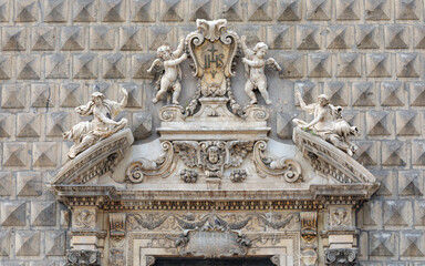 Unique facade of Gesù Nuovo Church in Naples, Italy. Built in Renaissance bugnato style, it features baroque sculptures of angels, saints, and a central shield with the letters "IHS"