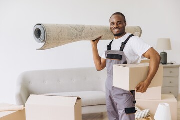 African American Mover Carrying Carpet and Box in New Apartment