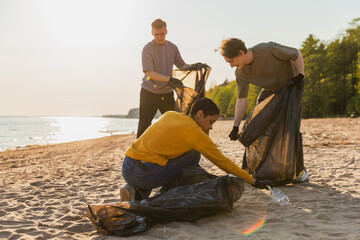 Earth day. Volunteers activists collects garbage cleaning of beach coastal zone. Woman and mans...