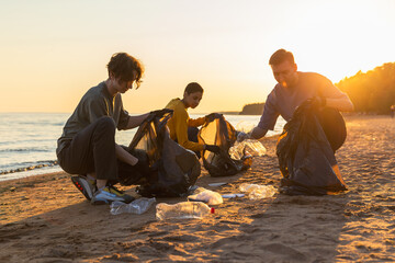 Earth day. Volunteers activists team collects garbage cleaning of beach coastal zone. Woman mans puts plastic trash in garbage bag on ocean shore. Environmental conservation coastal zone cleaning