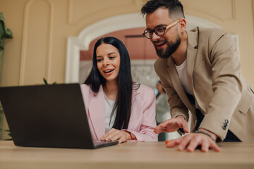 Business colleagues collaborating on laptop, sharing ideas and smiling