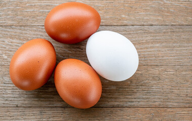 Fresh brown and white eggs arranged on a wooden table for culinary or farm-related use.
