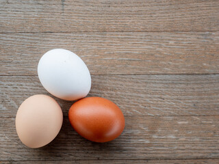 Three Easter eggs in various colors resting on a rustic wooden table.