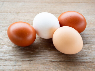 Four Easter eggs in various colors arranged on a rustic wooden table for festive celebrations.
