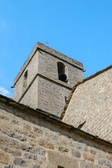 Fototapeta premium Stone Bell Tower Of Historic Romanesque Church In Guaso Huesca Spain. Ancient architecture detail, medieval building, clear blue sky, spiritual heritage