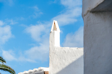 Whitewashed chimney of a traditional Mediterranean building against a clear blue sky. Architectural detail, white walls, sclassic design, charming village element, Binibeca Vell, Menorca