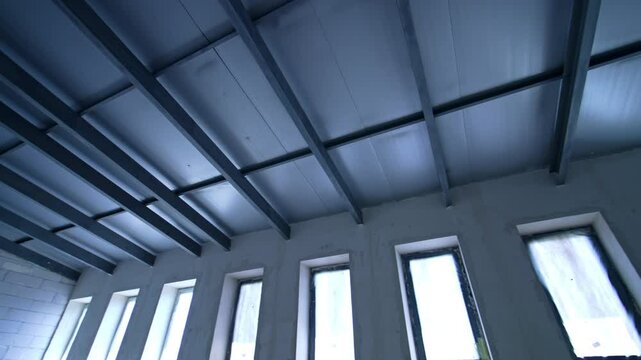 Modern ceiling design at site. Construction begins on contemporary building with sleek ceiling beams and large windows letting in natural light.
