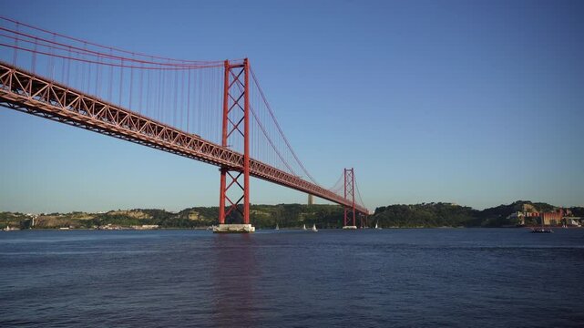 Stunning View of the Iconic Red Suspension Bridge over Calm Water Portugal