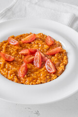 Creamy tomato risotto topped with cherry tomatoes on clean white plate