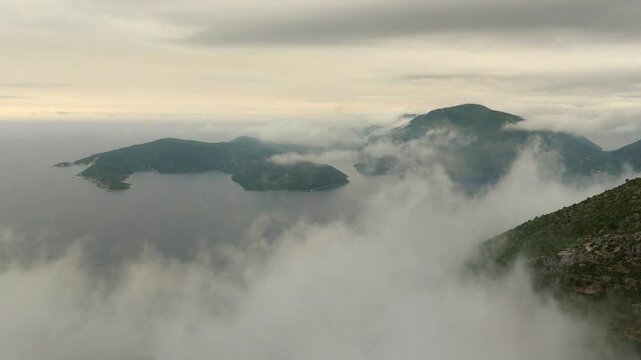 Aerial drone view of Ithaca flying through clouds foggy morning Greece Europe cinematic Vathy islands Ionian Mediterranean Sea 