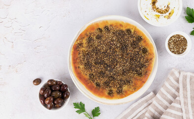 Flatbread Manakish with zaatar, olives, labneh on white background. Copy space. Top view.