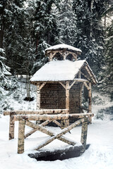Winter landscape. Gazebo and the bridge leading to it across the ravine made of birch logs in the city park.