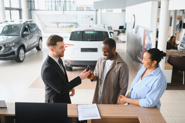 Car salesman giving keys to happy african american couple in dealership