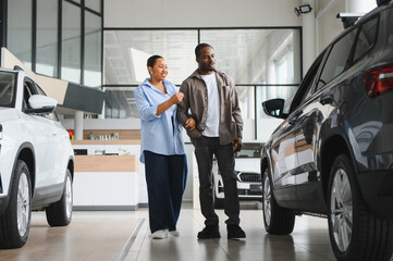 Saleswoman showing new car to couple in dealership